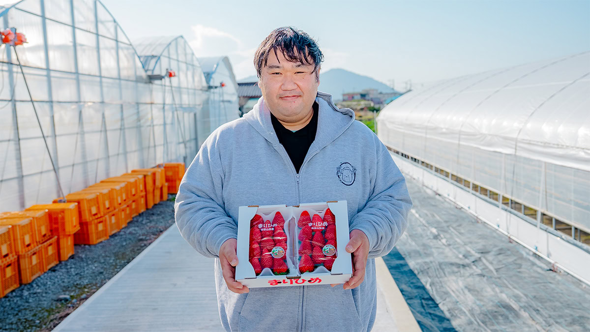 写真：大久保さんがパッケージされたイチゴを両手に持っている様子